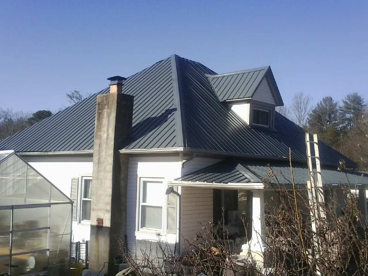 Dark blue standing seam metal roof on a white farmhouse with dormer — Slate & Tile Roof Repair by Roofing Brothers in Sandy Level