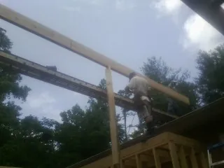 Carpenter setting a ridge beam over a new addition frame — Ice Dam Removal by Roofing Brothers in Sandy Level
