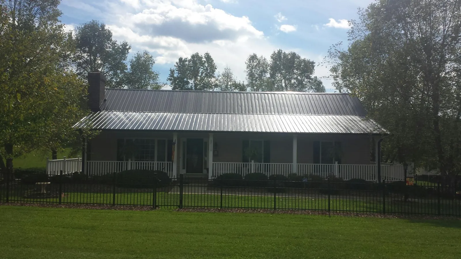 Gray metal roof on a brick ranch with a full width front porch — Gutter Guard Installation work by our crew in Sandy Level
