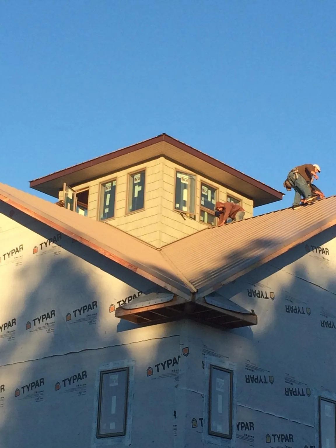 Roofers working around a rooftop cupola on a new metal roof at sunset — Roof Waterproofing in Sandy Level by Roofing Brothers